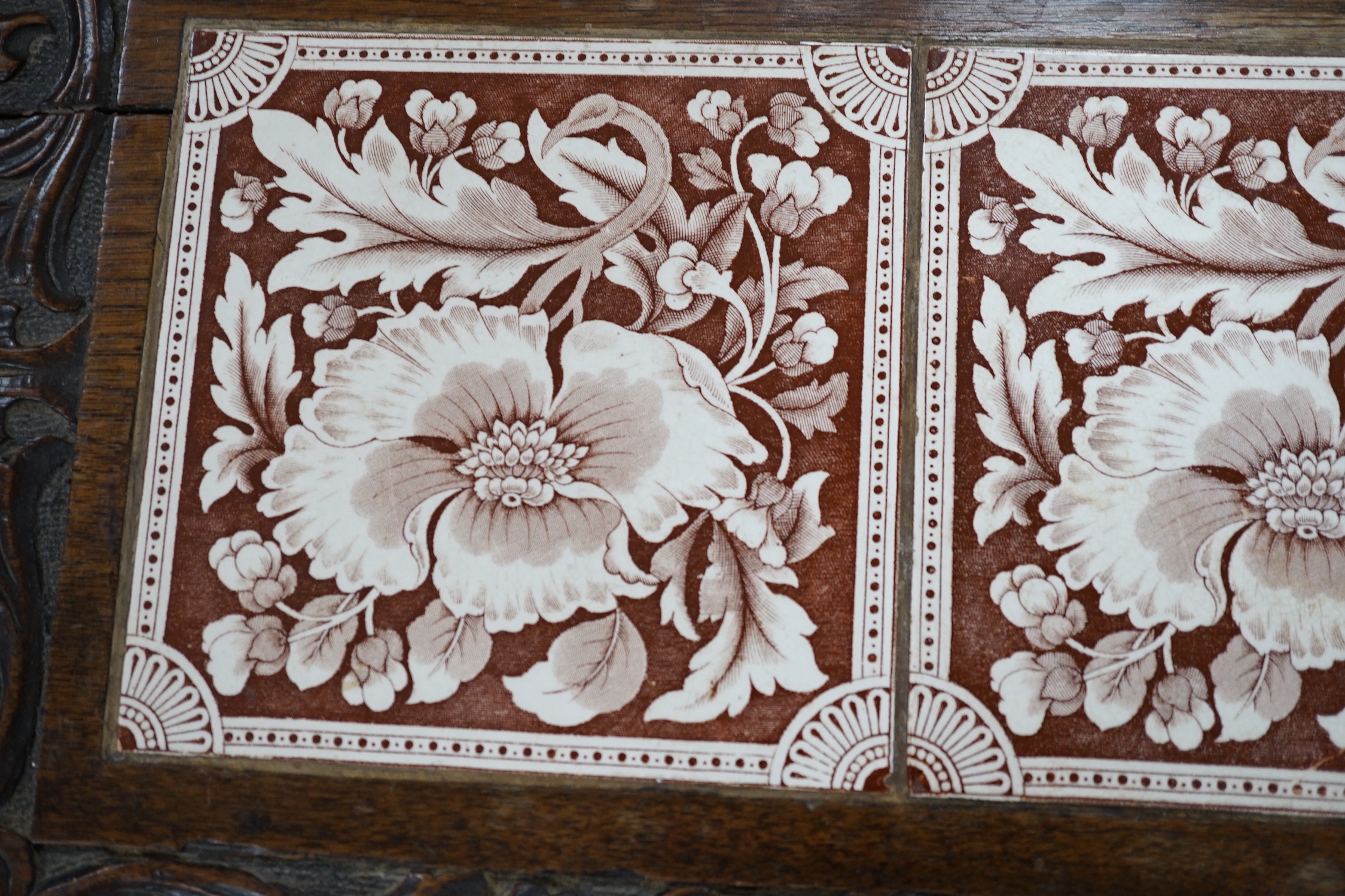 A Victorian carved oak stand inset with there floral tiles, 69cm wide